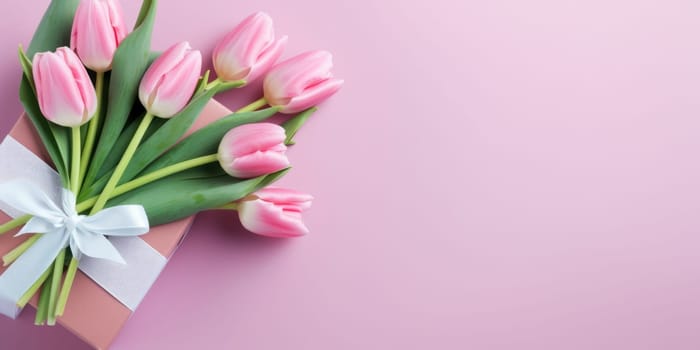 Wonderful spring tulips with gift box on the light pink background. Top view image. Copy space.