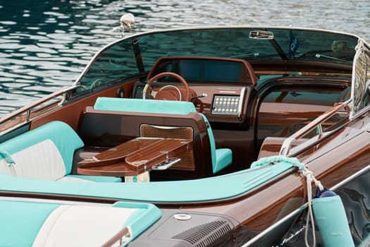 Monaco, Monte Carlo, 29 September 2022 - the wooden side of the luxury motor boat Riva in port of Hercules, sunny glare of the sun, elegance boat, glossy surfaces shine in sunny weather. High quality photo