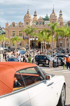 Monaco, Monte-Carlo, 29 September 2022 - Famous square Casino Monte-Carlo at sunny day, the red roof of a Rolls Royce convertible, luxury cars, wealth life, tourists take pictures of the landmark. High quality photo