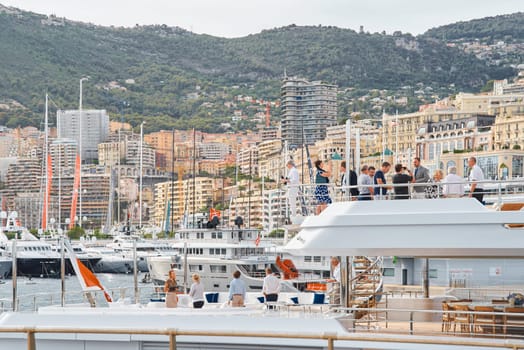 Monaco, Monte Carlo, 29 September 2022 - Invited wealthy clients inspect mega yachts at the largest fair exhibition in the world yacht show MYS, port Hercules, yacht brokers, sunny weather. High quality photo