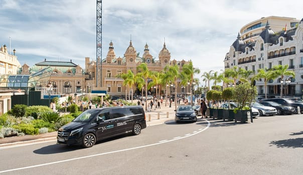 Monaco, Monte-Carlo, 29 September 2022 - Square Casino Monte-Carlo at sunny day, luxury cars, famous Hotel de Paris, wealth life, tourists take pictures of the landmark, pine trees, flowers. High quality photo