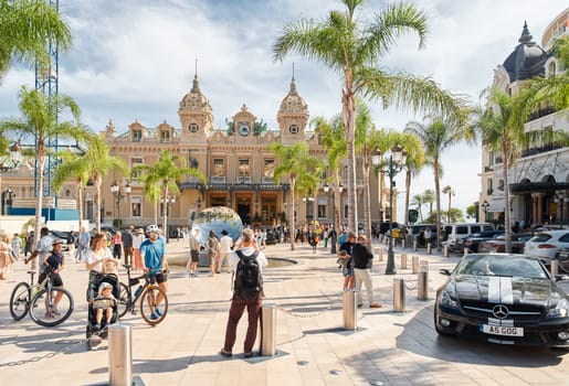 Monaco, Monte-Carlo, 29 September 2022 - Square Casino Monte-Carlo at sunny day, luxury cars, famous Hotel de Paris, wealth life, tourists take pictures of the landmark, pine trees, flowers. High quality photo