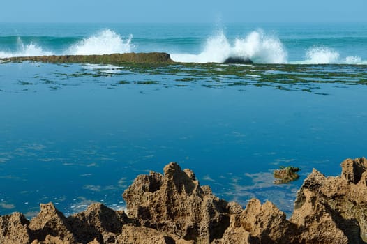 Beautiful waves splashing while crashing on the cliff. A mirror bay formed between rocks on the Atlantic ocean. Beauty in nature. Landscape.