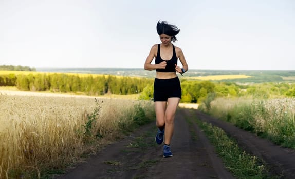 Young sports girl in a top and shorts trains outdoors, runs at sunset. A woman is engaged in trail running outdoor, preparing for a long race.
