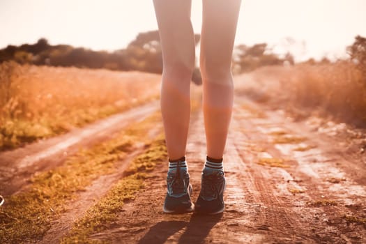 Young sports girl in a top and shorts trains outdoors, runs at sunset in the evening. A woman is engaged in trail running outdoor, preparing for a long race.