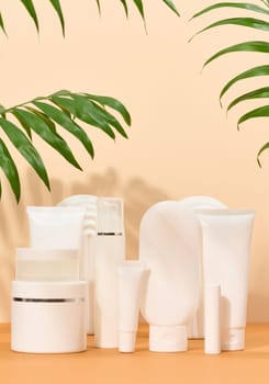 White plastic tubes, jars on a beige background, containers for cosmetic creams and gels, advertising and brand promotion