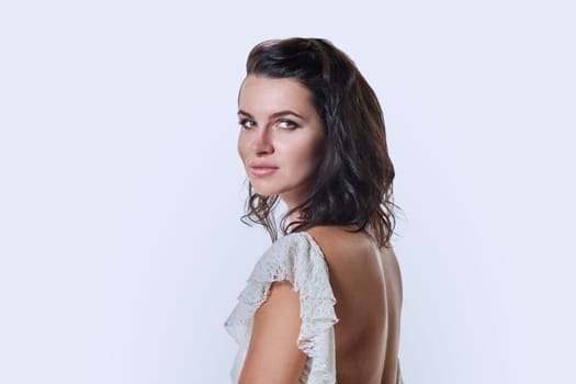 Beautiful sensual romantic young woman in white dress on white studio background looking at camera. Beauty, fashion, style concept