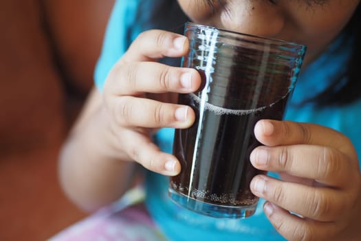 child drinking glass of soft drinks .