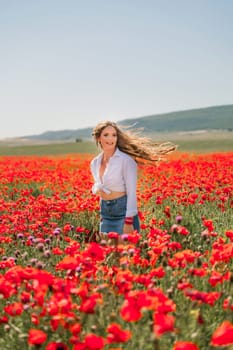 Happy woman in a poppy field in a white shirt and denim skirt with a wreath of poppies on her head posing and enjoying the poppy field