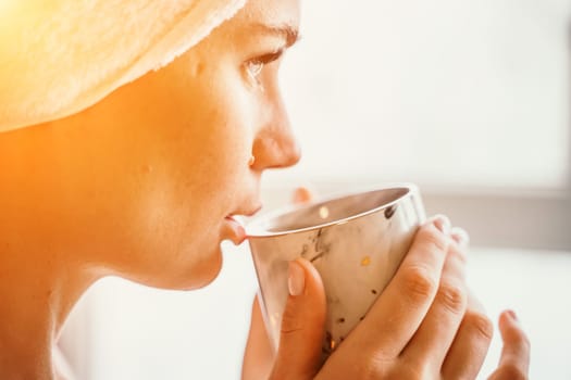 Young serene relaxed woman in spa bath towel drinking hot beverage tea coffee after taking shower bath at home. Beauty treatment, hydration concept