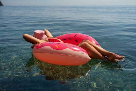 Summer vacation woman in hat floats on an inflatable donut mattress. Happy woman relaxing and enjoying family summer travel holidays travel on the sea