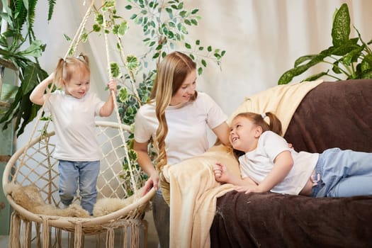 Happy family young mother babysitter relax having fun with cute little children daughters in living room at home