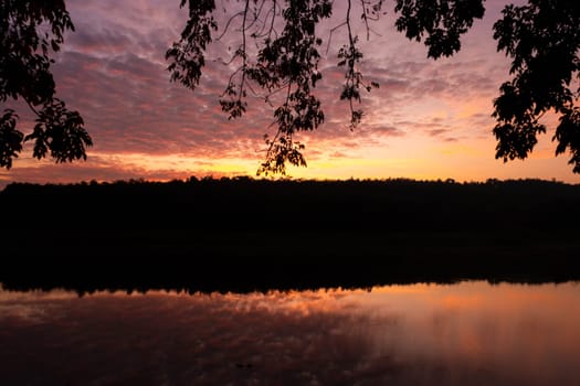 Beautiful nature morning with orange, yellow sunshine and fluffy clouds. Beautiful colorful dramatic sky with clouds at sunset or sunrise by the lake.