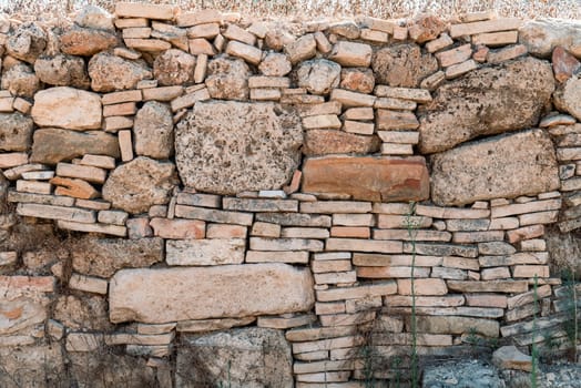 Old and irregular stack stone wall on a sunny day