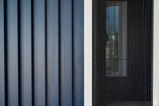 House with a facade covered with dark blue PVC panels and fly screen applied to the windows