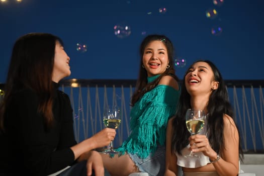 Cheerful young friends gathered together having fun enjoy chill at outdoor rooftop party with drinks