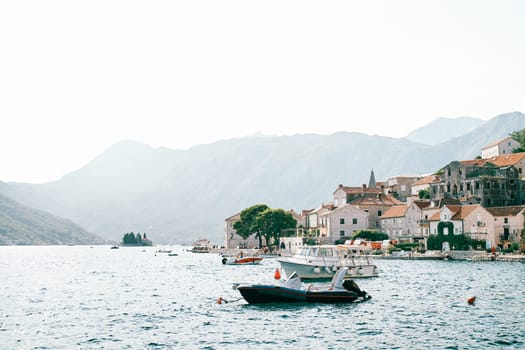 Yachts are moored off the coast of the ancient town of Perast at the foot of the mountains. Montenegro. High quality photo