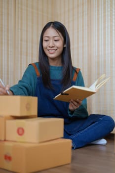 Starting small business entrepreneur of independent young Asian woman online seller is using computer and taking orders to pack products for delivery to customers. SME delivery concept.