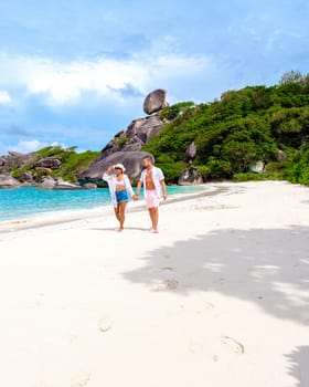 A couple of Asian women and white men relaxing on the beach in the sun at the Similan Islands in Thailand Phannga. couple visit the Similan Islands on a boat trip during vacation