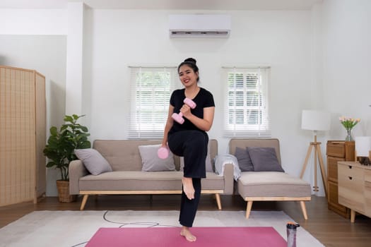 Fat woman exercising at home A beautiful oversized woman in a sports bra and casual pants stands in the living room and exercises..