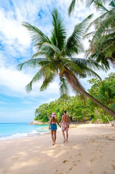 Phuket Thailand, a couple of men and woman walking at the beach of Surin, Surin Beach Phuket. A couple walking on a tropical beach with palm trees