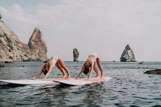 Woman sup yoga. Middle age sporty woman practising yoga pilates on paddle sup surfboard. Female stretching doing workout on sea water. Modern individual hipster outdoor summer sport activity