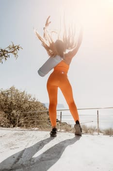 Fitness woman sea. Outdoor workout on yoga mat in park near to ocean beach. Female fitness pilates yoga routine concept. Healthy lifestyle. Happy fit woman exercising with rubber band in park.