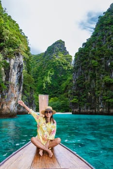 Asian women in front of a longtail boat at Kho Phi Phi Thailand, women in front of a boat at Pileh Lagoon with turqouse colored ocean during a boat trip to Maya Bay Koh Phi Phi