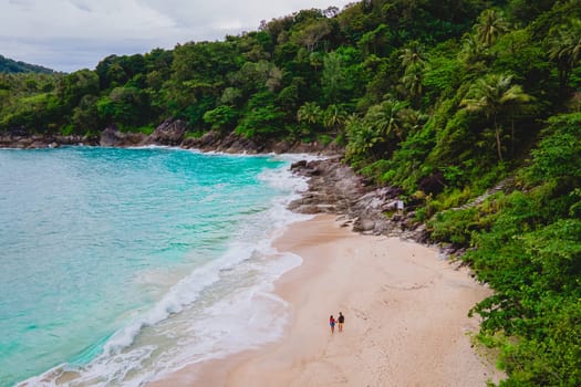 A couple of men and women are relaxing on a white tropical beach with palm trees in Phuket Thailand. Freedom Beach Phuket on a sunny day, secret tropical beach