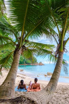 A couple of men and women are relaxing on a white tropical beach with palm trees in Phuket Thailand. Banana Beach Phuket on a sunny day in Thailand