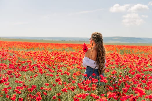 Woman poppies field. Side view of a happy woman with long hair in a poppy field and enjoying the beauty of nature in a warm summer day