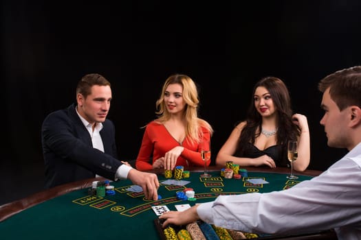 Friends enjoying a gambling night. Young people sit at the game table. The dealer deals the cards