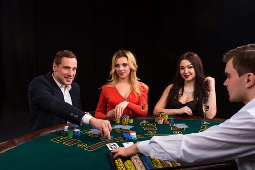 Friends enjoying a gambling night. Young people sit at the game table. The dealer deals the cards