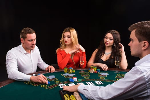 Friends enjoying a gambling night. Young people sit at the game table. The dealer deals the cards