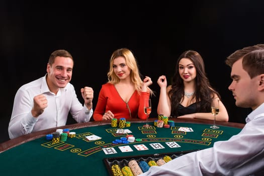 Friends enjoying a gambling night. Young people sit at the game table. The dealer deals the cards