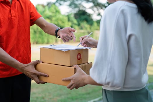 Young woman signature in document to receive package from professional delivery man at home.