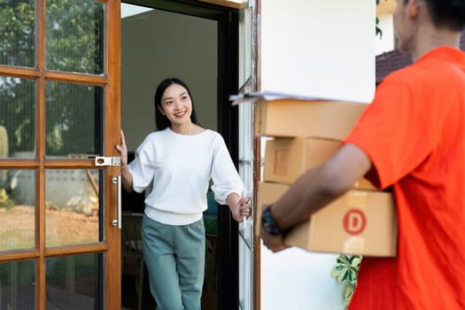 Young Asian cute girl receiving boxes from postman at the door. Delivery concept.