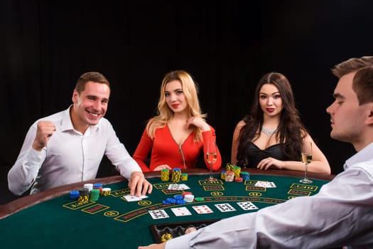 Friends enjoying a gambling night. Young people sit at the game table. The dealer deals the cards