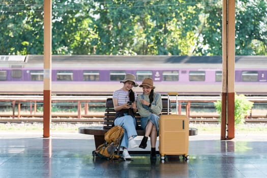 Asian woman friends at railway station have happy moment. Tourism and travel.