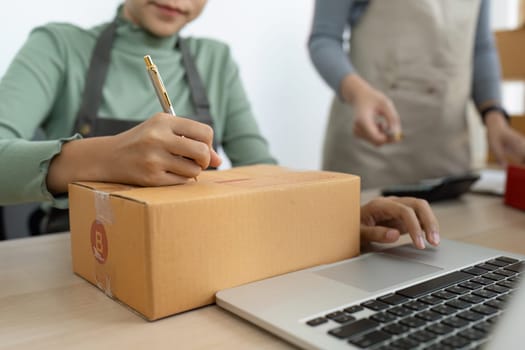 Asian woman write parcel box to prepare for delivery to customer. e-business concept.