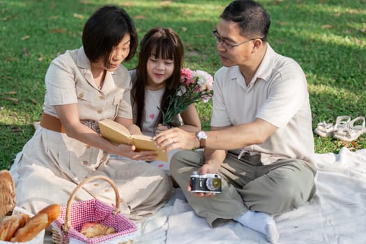 happy smiling family grandparent and grandchild picnic together outside at park.