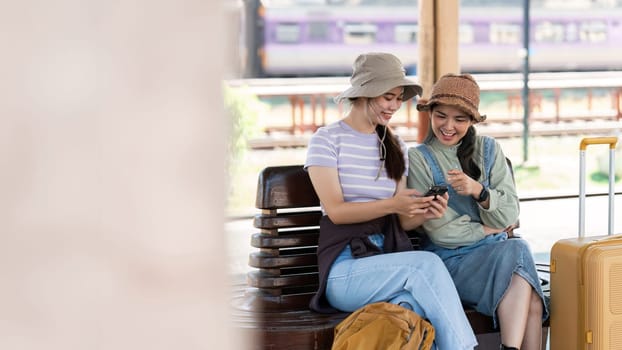 Asian woman friends at railway station have happy moment. Tourism and travel.