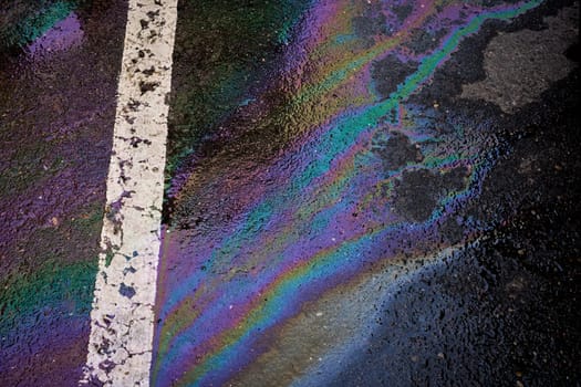 Oil, gasoline, or oil spill on wet asphalt with a parking lot and a dividing line