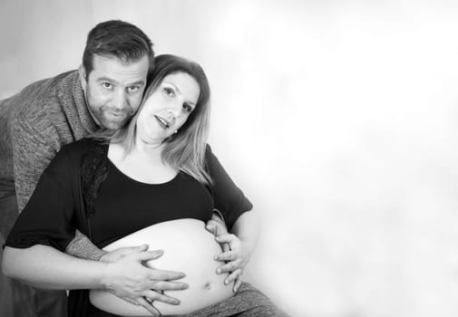 Eight months pregnant woman and dad hugging her. Happy expression