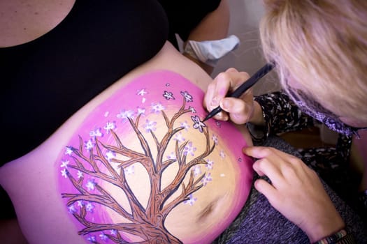 Girl drawing on belly of pregnant woman. No copy space