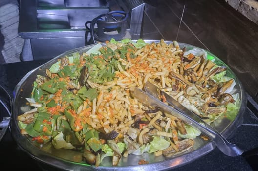 Appetizing dish: rice along with various vegetables and mushrooms on a metal frying pan in a restaurant.