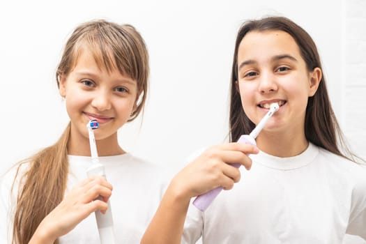 Portrait of two beautiful girls kids with perfect smile holding toothbrushes. Child dental care, oral hygiene concept. High quality photo