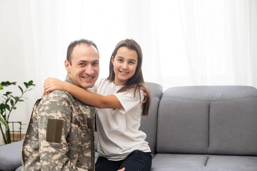 Young man in military uniform with his wife on sofa at home. High quality photo