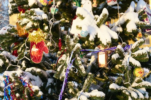decorated Christmas tree outside in winter. Christmas toys and decorations. Garland balls and tinsel