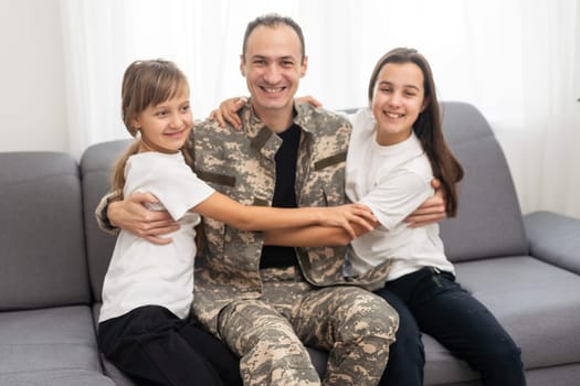 Little children hugging their military father at home. High quality photo